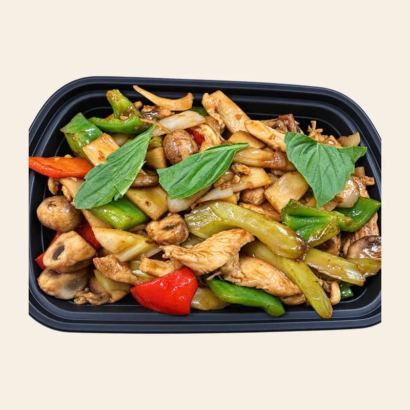 Chicken Thai basil with peppers, mushrooms and basil leaves in a take-out tray